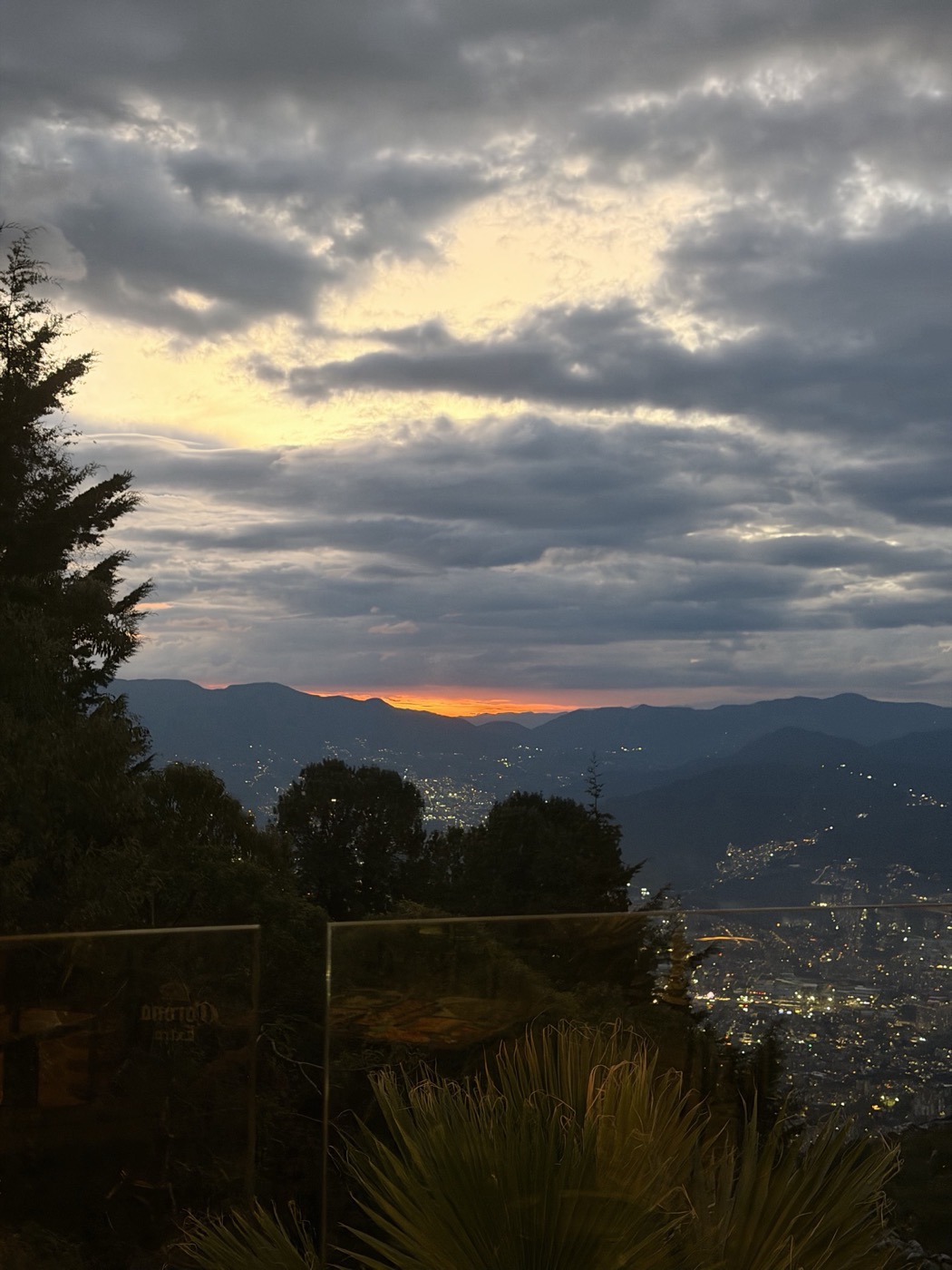 A valley at dusk from above, the city lights coming on